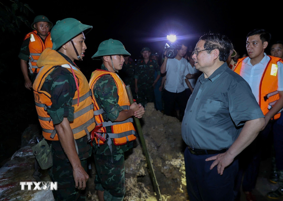 Thủ tướng Phạm Minh Chính động viên lực lượng đang đắp chống tràn, bảo đảm an toàn tuyến đê hữu Cầu. (Ảnh: Dương Giang/TTXVN)