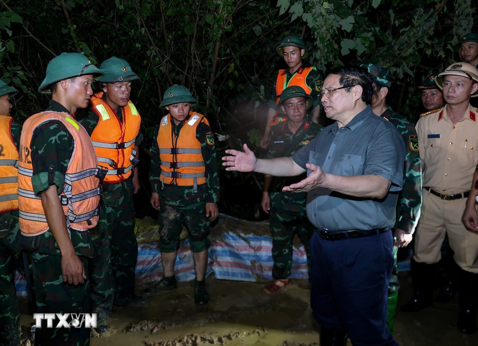 Thủ tướng Phạm Minh Chính động viên lực lượng đang đắp chống tràn, bảo đảm an toàn tuyến đê hữu Cầu. (Ảnh: Dương Giang/TTXVN)