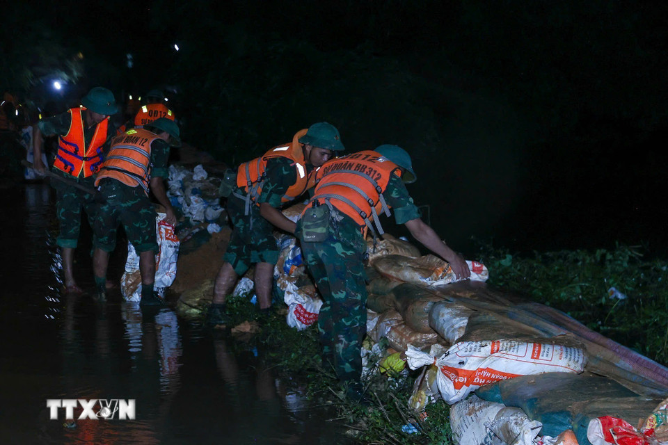 Lực lượng quân đội đang đắp chống tràn, bảo đảm an toàn tuyến đê hữu Cầu. (Ảnh: Dương Giang/TTXVN)