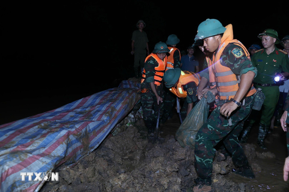 Các lực lượng đắp đê chống tràn, bảo đảm an toàn tuyến đê hữu Cầu. (Ảnh: Dương Giang/TTXVN)