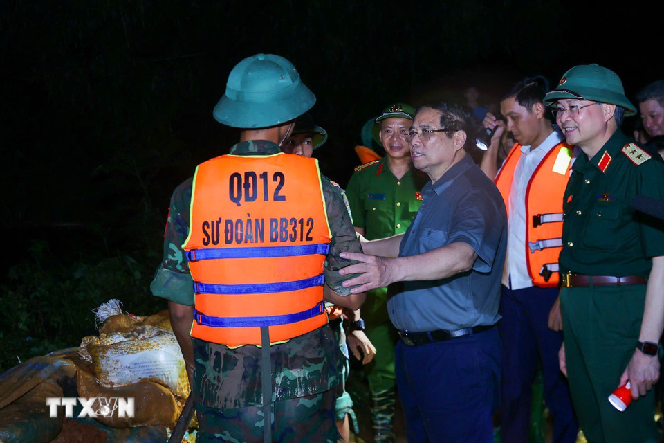 Thủ tướng Phạm Minh Chính động viên lực lượng đang đắp chống tràn, bảo đảm an toàn tuyến đê hữu Cầu. (Ảnh: Dương Giang/TTXVN)