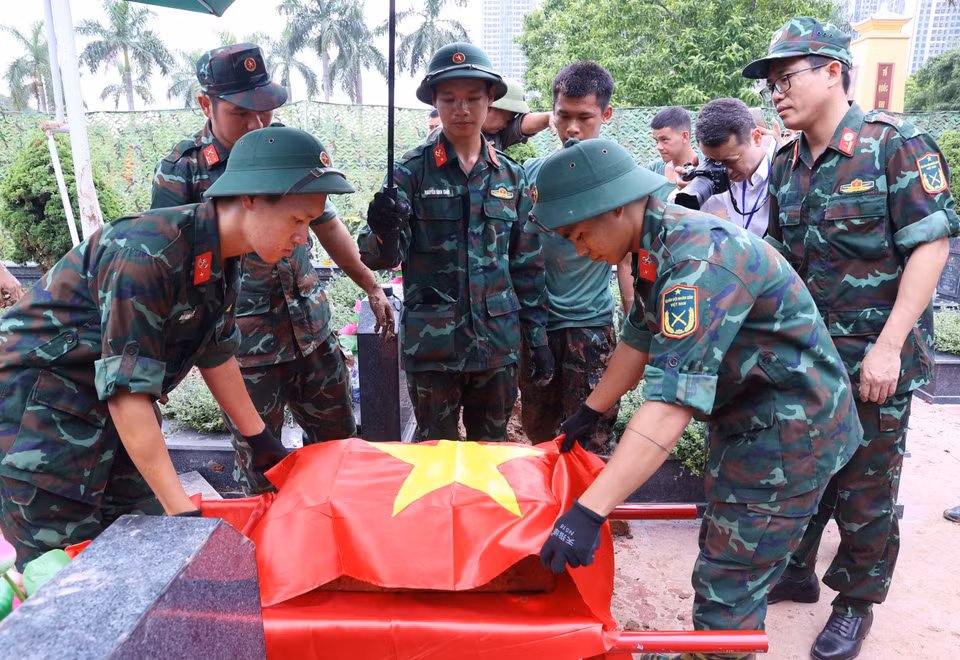 Thực hiện nghi thức phủ Quốc kỳ trang trọng, tri ân Anh hùng liệt sỹ đã hy sinh vì độc lập, tự do của Tổ quốc tại Nghĩa trang Mai Dịch (phường Phú Diễn). (Ảnh: Văn Điệp/TTXVN)