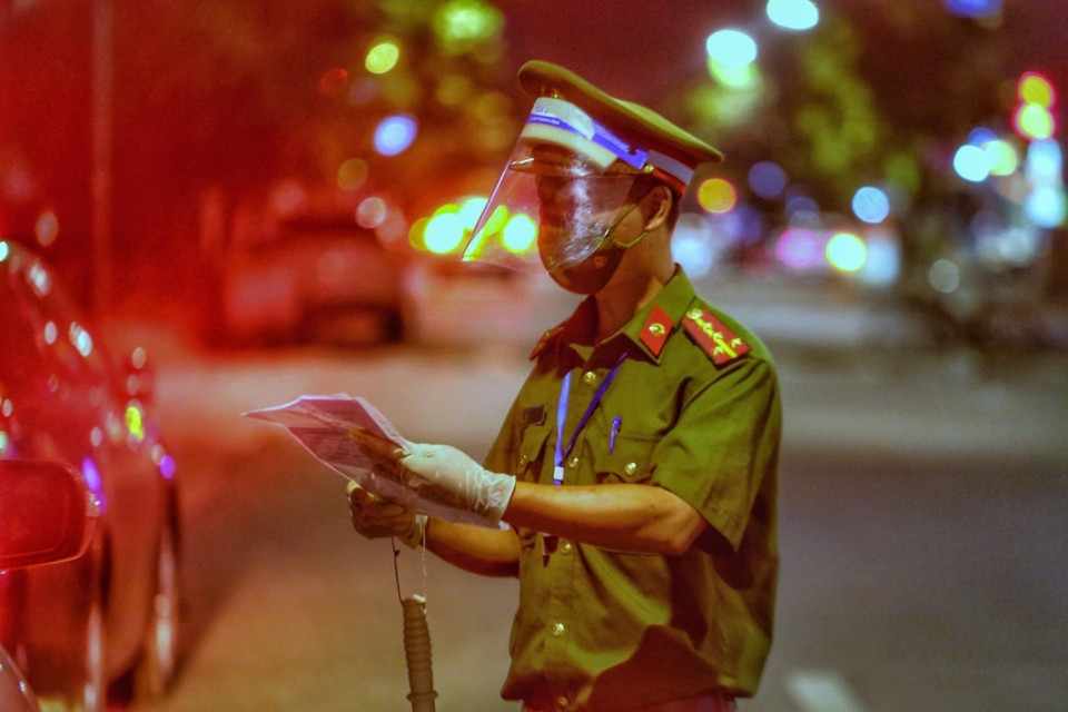 Lực lượng chức năng kiểm tra giấy tờ người đi đường tại chốt kiểm soát phố Huế. (Ảnh: Tuấn Đức/TTXVN)