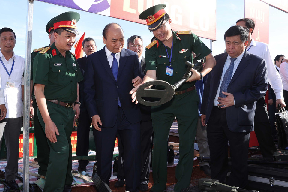 Thủ tướng Nguyễn Xuân Phúc nghe các đơn vị quốc phòng giới thiệu về các thiết bị rà phá bom mìn, đảm bảo an toàn trong quá trình thi công dự án. (Ảnh: Thống Nhất/TTXVN)