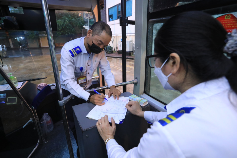 Lái xe Hoàng Quốc Bảo và nhân viên bán vé tuyến xe buýt BRT 01 Kim Mã-Yên Nghĩa ký lệnh điều động xe xuất bến Kim Mã. (Ảnh: Tuấn Anh/TTXVN)