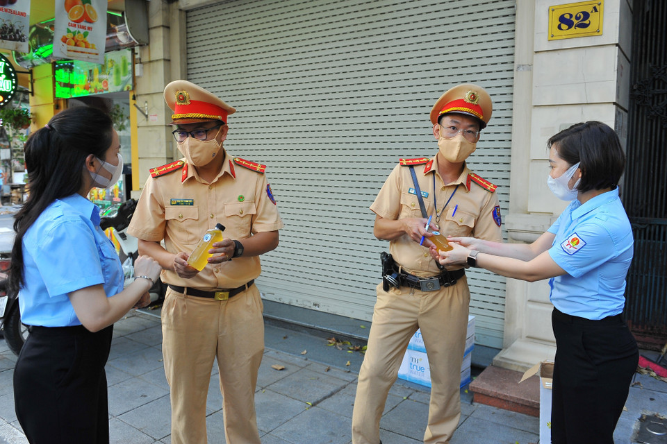 Trao tặng đồ uống cho lực lượng công an Thủ đô đang thực hiện nhiệm vụ tại 6 tổ tuần tra kiểm soát lưu động trên các tuyến đường. (Ảnh: Minh Đức/TTXVN)