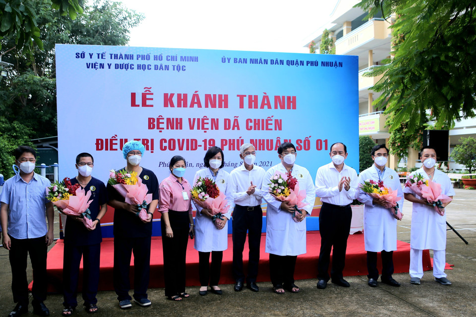 Lãnh đạo Ủy ban Nhân dân Thành phố Hồ Chí Minh và Sở Y tế tặng hoa, động viên các y, bác sỹ làm nhiệm vụ tại Bệnh viện dã chiến điều trị bệnh nhân COVID-19 số 01 Phú Nhuận. (Ảnh: Thành Chung/TTXVN)