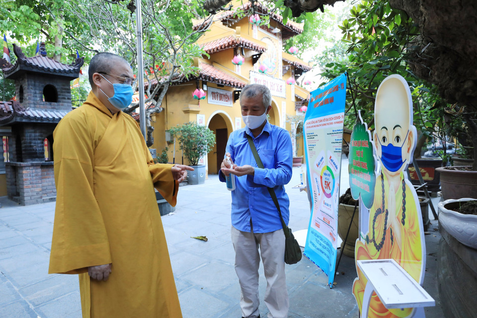 Hòa thượng Thích Thanh Nhiễu, Phó Chủ tịch thường trực Hội đồng Trị sự Giáo hội Phật giáo Việt Nam nhắc nhở người phục vụ trong chùa thực hiện phòng dịch theo thông điệp 5K khi vào chùa Quán Sứ. (Ảnh: Minh Đức/TTXVN)
