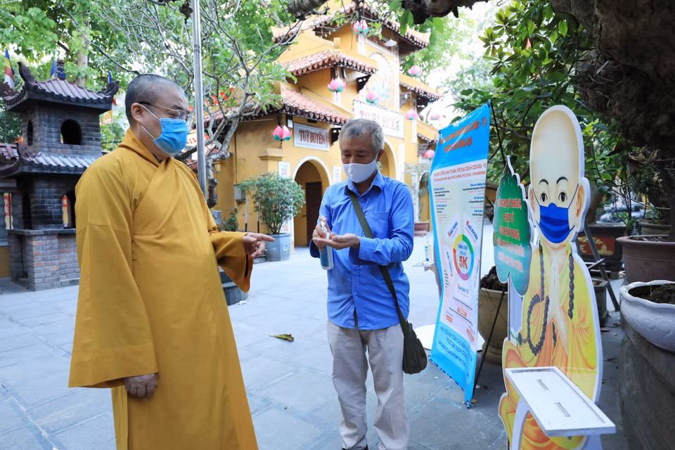 Hòa thượng Thích Thanh Nhiễu, Phó Chủ tịch thường trực Hội đồng Trị sự Giáo hội Phật giáo Việt Nam nhắc nhở người phục vụ trong chùa thực hiện phòng dịch theo thông điệp 5K khi vào chùa Quán Sứ. (Ảnh: Minh Đức/TTXVN)