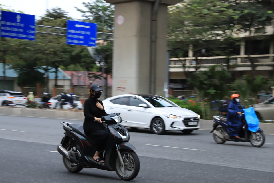 Thời tiết lạnh khiến nhiều người phải một tay điều khiển xe, một tay giữ áo để ngăn cái lạnh đầu mùa. (Ảnh: Hoài Nam/Vietnam+)