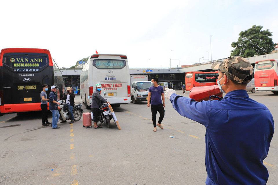 Anh Nguyễn Văn Hiếu, nhân viên bến xe Nước Ngầm luôn phải di chuyển và nhắc nhở người dân đeo khẩu trang trong khu vực bãi xe. (Ảnh: Hoài Nam/Vietnam+)