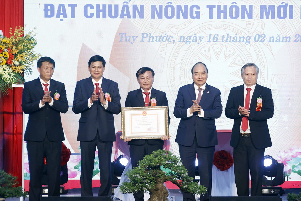 Chủ tịch nước Nguyễn Xuân Phúc trao Bằng chứng nhận huyện đạt chuẩn nông thôn mới cho lãnh đạo huyện Tuy Phước. (Ảnh: Thống Nhất/TTXVN) 