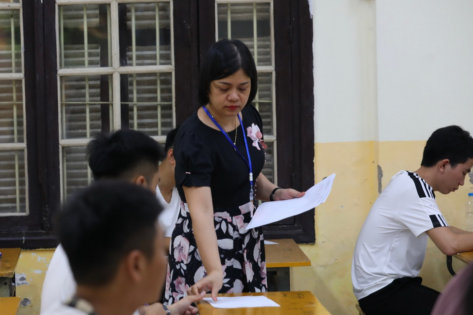 Giám thị phát giấy nháp cho thí sinh điểm thi Trường THPT Phan Đình Phùng, quận Ba Đình, Hà Nội. (Ảnh: Hoàng Hiếu/TTXVN)