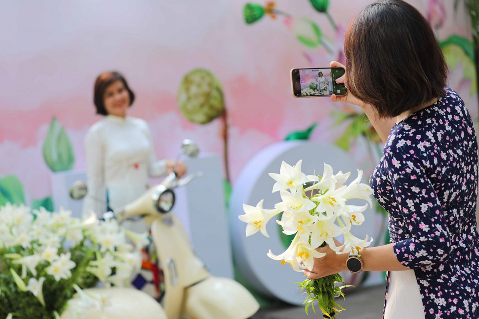 Ngày nghỉ lễ cũng là dịp để chị em phụ nữ xúng xính áo dài cùng lưu lại những khoảnh khắc đẹp của Hà Nội trong mùa hoa loa kèn. (Ảnh: Thanh Tùng/TTXVN)