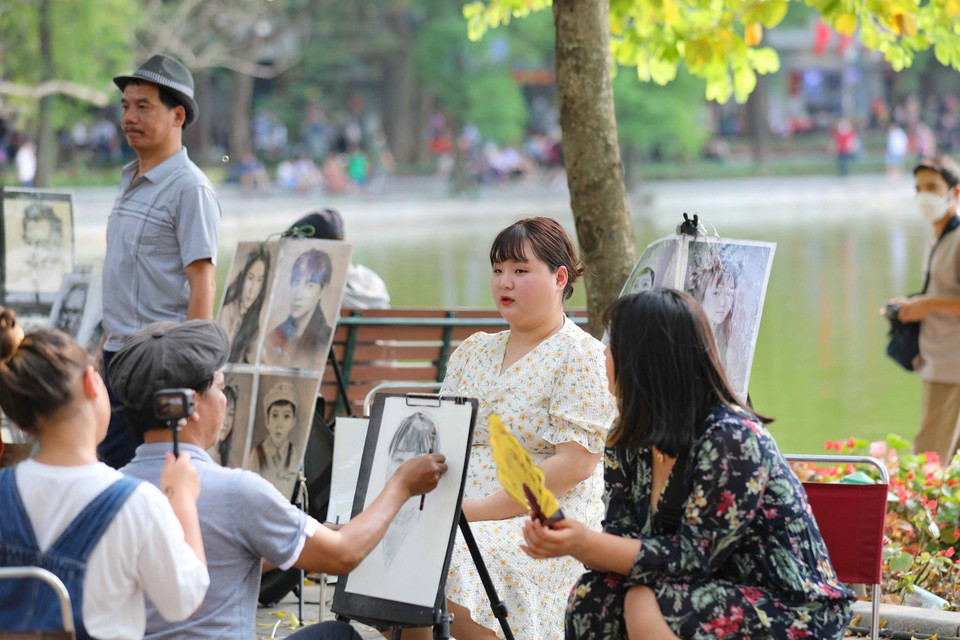 Du khách làm mẫu để có bức ký họa làm kỷ niệm cho mình khi đến với Hồ Gươm. (Ảnh: Thanh Tùng/TTXVN)