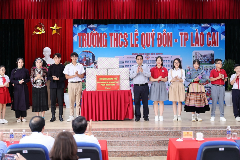 Thủ tướng Phạm Minh Chính tặng quà cho giáo viên, học sinh cụm liên trường học thành phố Lào Cai. (Ảnh: Dương Giang/TTXVN)