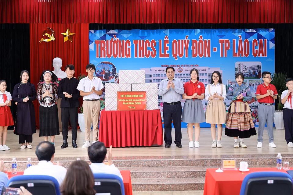 Thủ tướng Phạm Minh Chính tặng quà cho giáo viên, học sinh cụm liên trường học thành phố Lào Cai. (Ảnh: Dương Giang/TTXVN)