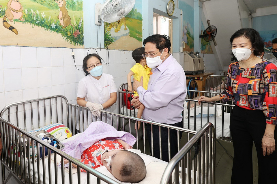 Thủ tướng Phạm Minh Chính đến tận giường thăm trẻ em đang được chăm sóc tại Trung tâm bảo trợ trẻ tàn tật mồ côi Thị Nghè. (Ảnh: Dương Giang/TTXVN)