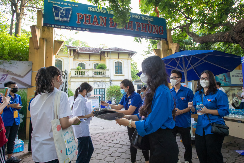 Tình nguyện viên phát quạt chống nóng cho các thí sinh. (Ảnh: PV/Vietnam+)