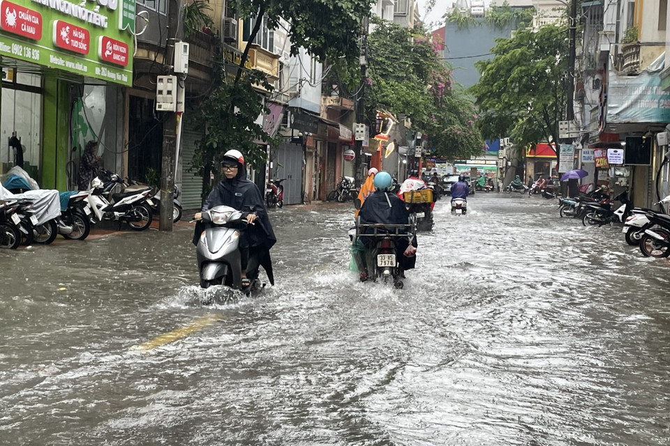 Mưa lớn gây ngập úng đến hết cả bánh xe máy trên con đường Hoàng Văn Thái (quận Thanh Xuân). (Ảnh: Minh Hiếu/Vietnam+)