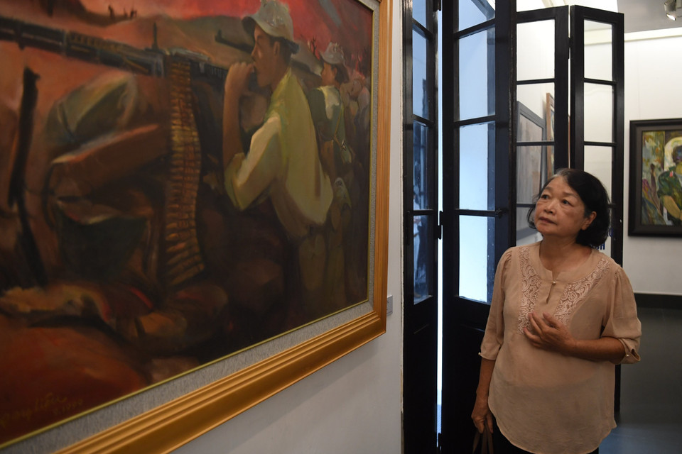 Đứng trước tác phẩm của người chồng quá cố - họa sỹ Phạm Ngọc Liệu, bà Nguyễn Thị Trâm (quận Hà Đông, Hà Nội) bồi hồi kể lại quá trình hoàn thành tác phẩm “Quảng Trị năm 1972”. Ký họa này được ông Liệu thực hiện khi còn đang là sinh viên trường Mỹ thuật và trong chuyến đi thực tế vào tỉnh Quảng Trị năm 1972. (Ảnh: Minh Hiếu/Vietnam+)