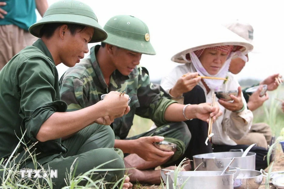 Bữa cơm của bộ đội và nhân dân trong ngày gặt lúa "chạy lũ" năm 2009. (Ảnh: Tràng Dương/TTXVN)