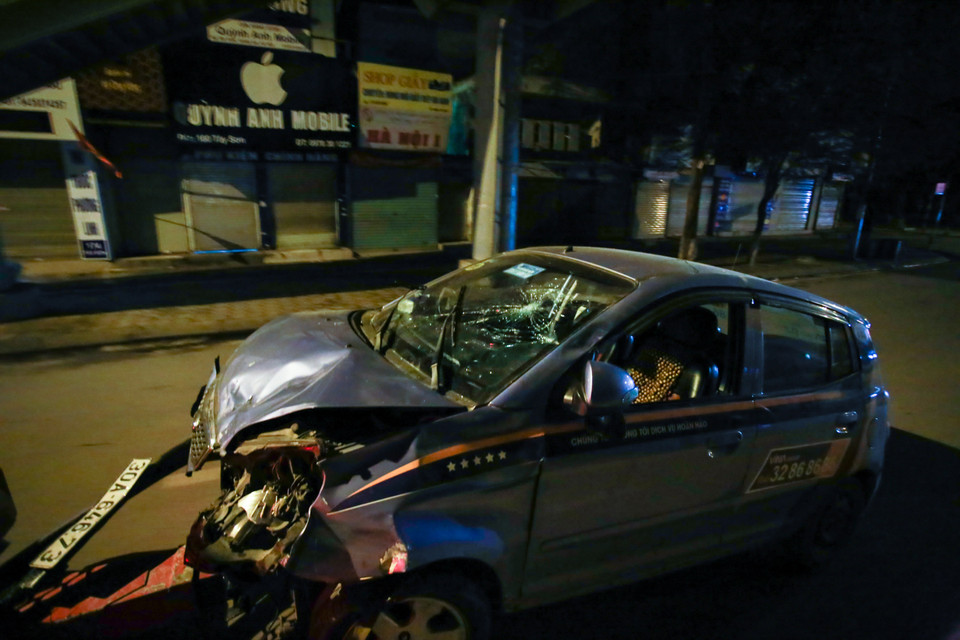 Phần đầu chiếc taxi móp méo, mặt kính xe bị đập vỡ không rõ nguyên do. (Ảnh: Minh Sơn/Vietnam+)
