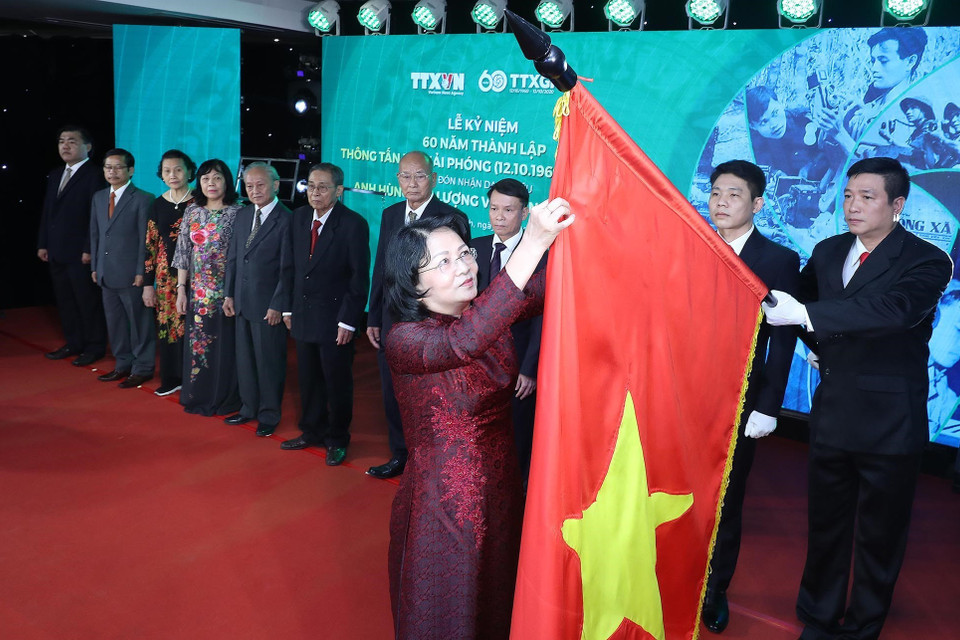 Thừa ủy quyền của Chủ tịch nước, Phó Chủ tịch nước Đặng Thị Ngọc Thịnh gắn Danh hiệu Anh hùng Lực lượng vũ trang nhân dân tặng Thông tấn xã Giải phóng lên lá cờ truyền thống của TTXVN. (Ảnh: Lâm Khánh/TTXVN)