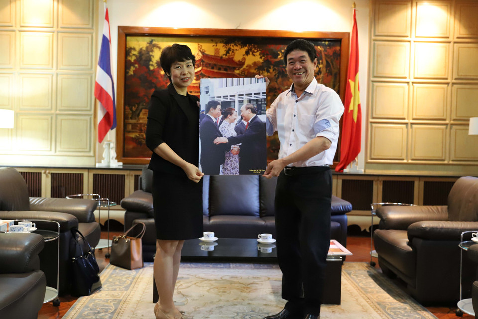 Phó Tổng giám đốc TTXVN Vũ Việt Trang tặng quà lưu niệm là tác phẩm ảnh của phóng viên TTXVN cho Đại sứ Việt Nam tại Thái Lan Nguyễn Hải Bằng. (Ảnh: Ngọc Quang-Hữu Kiên/TTXVN)