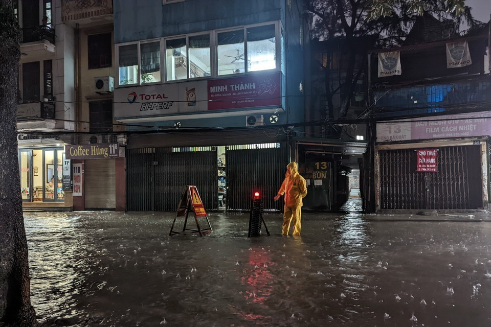 Công nhân Công ty Thoát nước Hà Nội ứng trực, cảnh báo khu vực ngập. (Ảnh: Mạnh Khánh/TTXVN)
