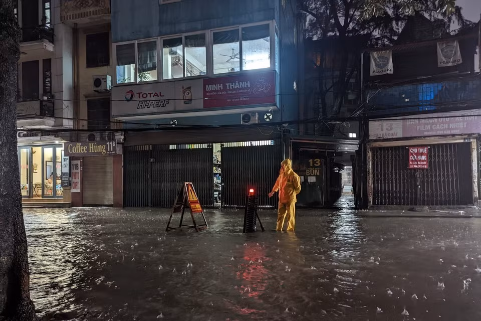 Công nhân Công ty Thoát nước Hà Nội ứng trực, cảnh báo khu vực ngập. (Ảnh: Mạnh Khánh/TTXVN)