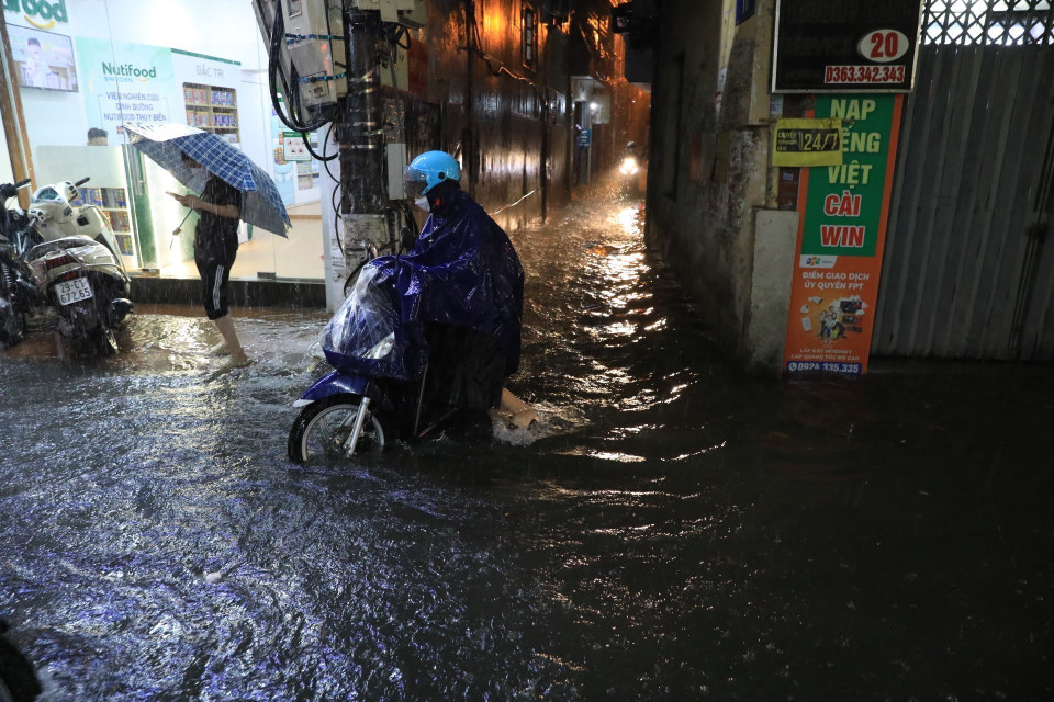 Nhiều người phải đẩy xe đi qua chỗ ngập trên phố Bùi Xương Trạch, quận Thanh Xuân. (Ảnh: Tuấn Anh/TTXVN)