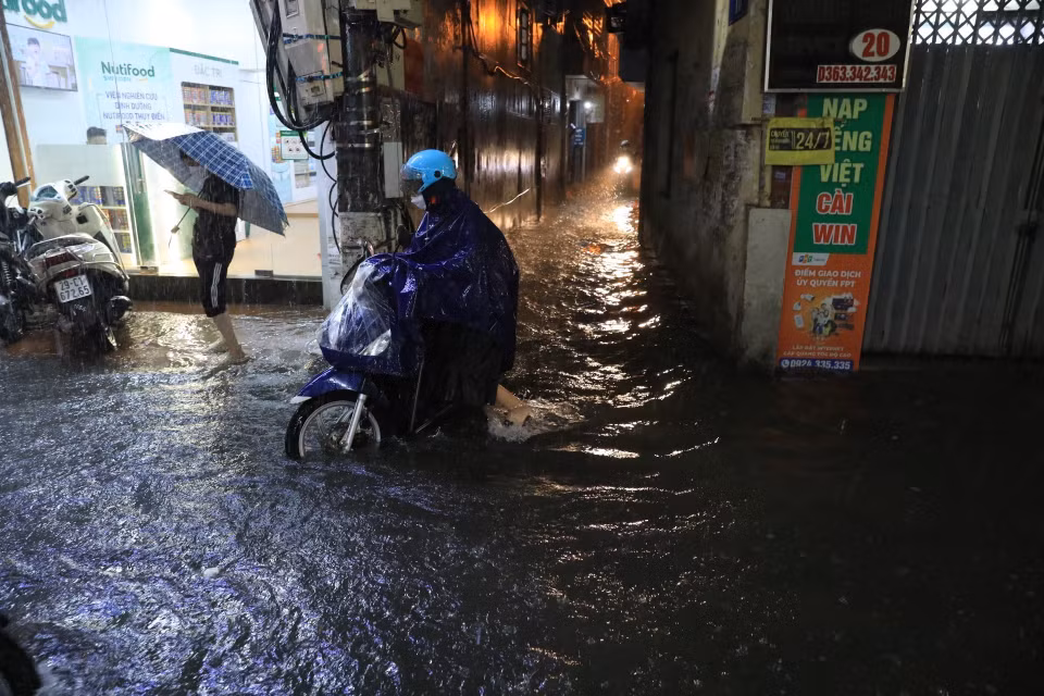 Nhiều người phải đẩy xe đi qua chỗ ngập trên phố Bùi Xương Trạch, quận Thanh Xuân. (Ảnh: Tuấn Anh/TTXVN)