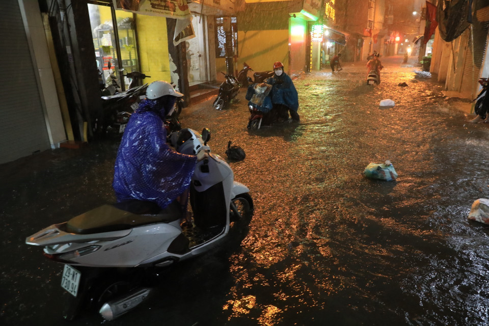 Phố Bùi Xương Trạch ngập nặng khiến nhiều người đi lại khó khăn. (Ảnh: Tuấn Anh/TTXVN)