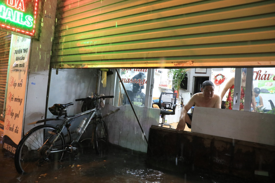 Phố Bùi Xương Trạch ngập nặng khiến người dân phải tìm cách ngăn không cho nước tràn vào nhà. (Ảnh: Tuấn Anh/TTXVN)