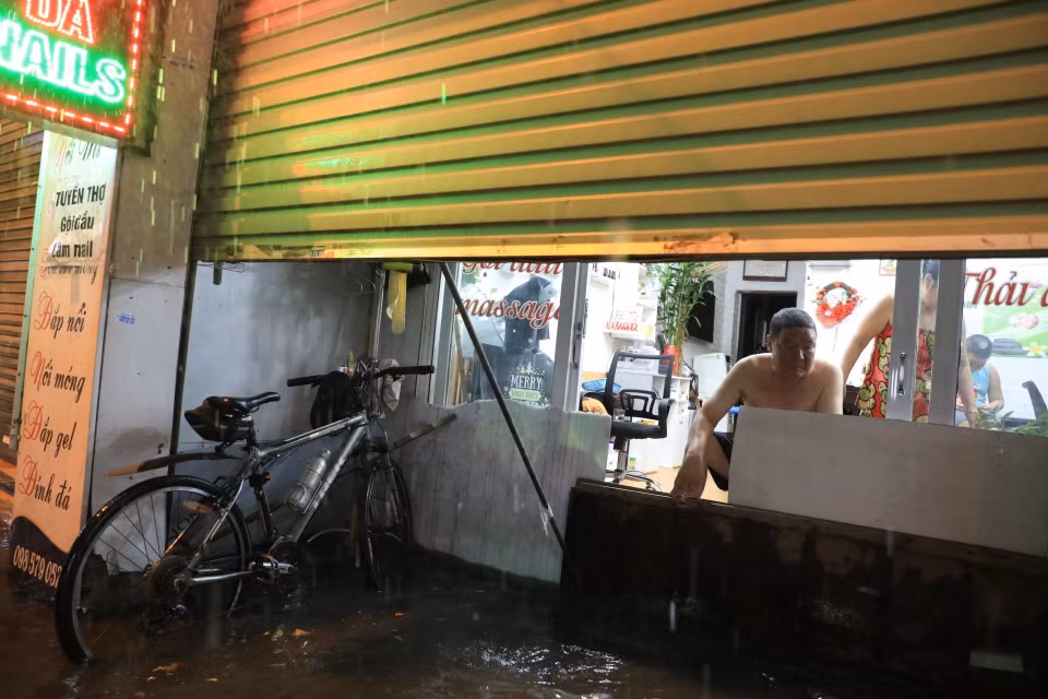 Phố Bùi Xương Trạch ngập nặng khiến người dân phải tìm cách ngăn không cho nước tràn vào nhà. (Ảnh: Tuấn Anh/TTXVN)