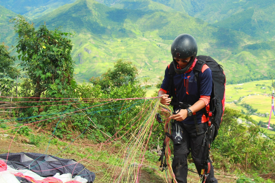 Một phi công kiểm tra dây dù trước khi bay. (Ảnh: Xuân Mai/Vietnam+)
