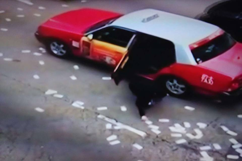 Lái xe taxi dừng xe giữa đường để chạy xuống nhặt tiền. (Nguồn: CCTV)