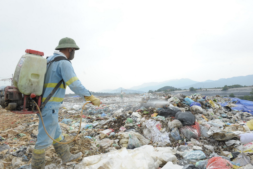 Công nhân Công ty TNHH MTV Môi trường Đô thị Hà Nội phun thuốc phòng trừ muỗi tại bãi rác Nam Sơn. (Ảnh: Mạnh Khánh/TTXVN)