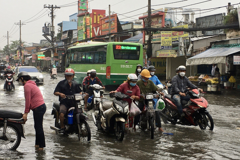 Người dân vất vả di chuyển giữa dòng nước ngập trên Quốc lộ 30. (Ảnh: Thanh Vũ/TTXVN)