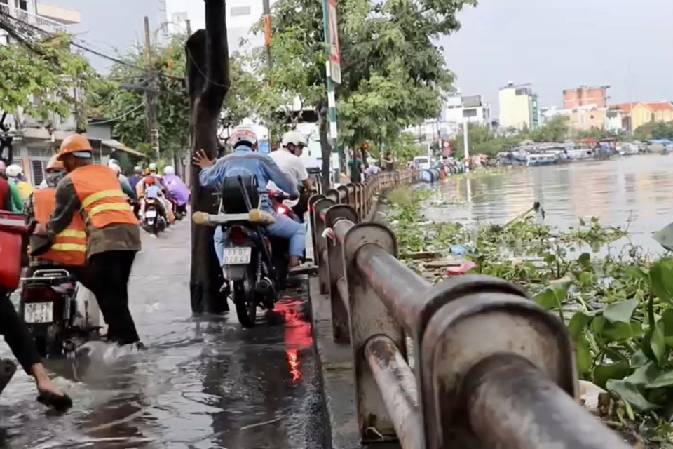 Người dân vất vả di chuyển giữa nước ngập trên đường Trần Xuân Soạn, quận 7. (Ảnh: Thanh Vũ/TTXVN)