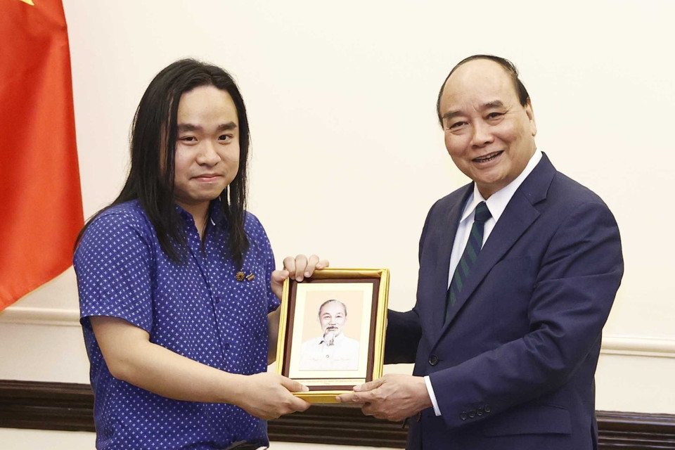 Chủ tịch nước Nguyễn Xuân Phúc tặng ảnh Chủ tịch Hồ Chí Minh cho dịch giả trẻ Nguyễn Bình. (Ảnh: Thống Nhất/TTXVN)