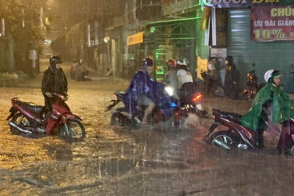 Người dân dắt xe bị chết máy giữa làn nước trên đường số 10, thành phố Thủ Đức. (Ảnh: Hồng Giang/TTXVN)