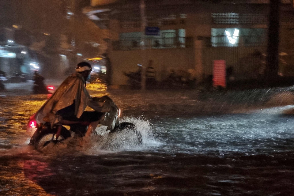 Người dân vượt làn nước ngập trên đường Ung Văn Khiêm, quận Bình Thạnh. (Ảnh: Hồng Giang/TTXVN)