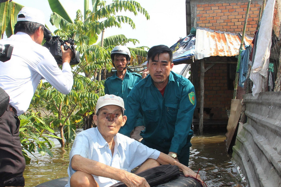 Sơ tán người già ra khỏi khu vực bị ngập nặng. (Ảnh: Thanh Liêm/TTXVN)