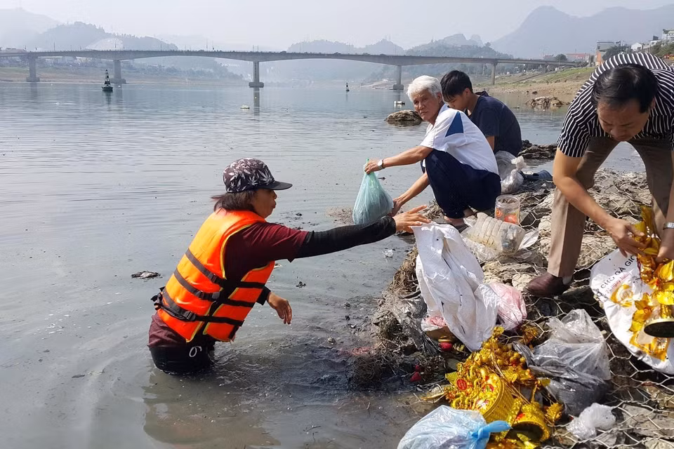 Người dân thành phố Hòa Bình, tỉnh Hòa Bình đi thu gom túi nylon vứt trên sông Đà trong ngày Tết Táo quân để bảo vệ môi trường. (Ảnh: Thanh Hải/TTXVN)