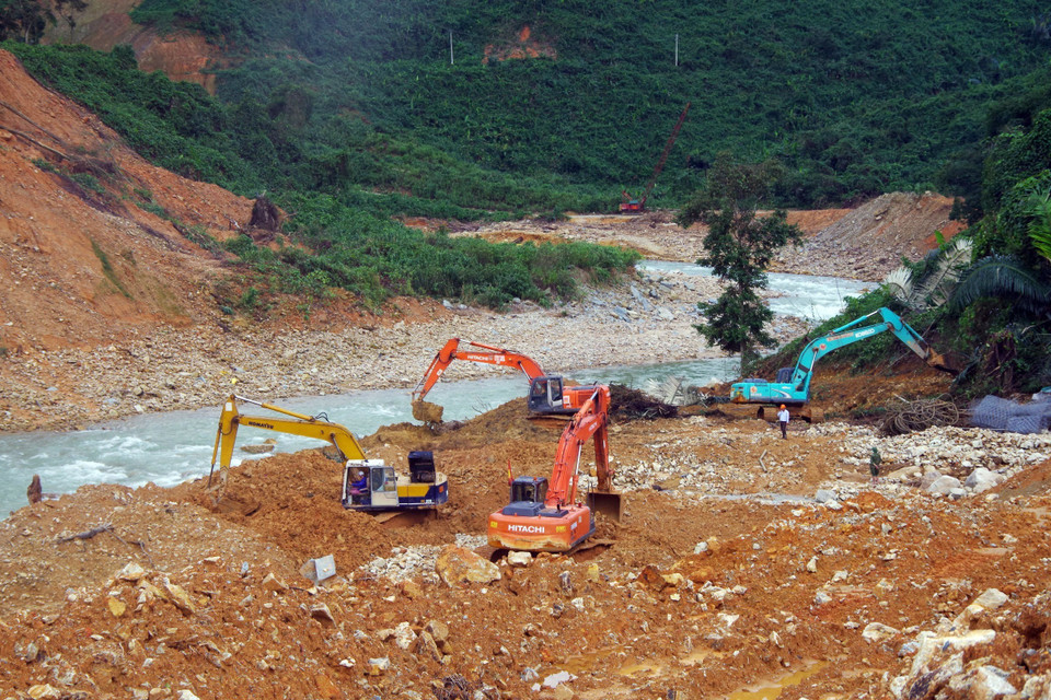  Lực lượng cơ giới múc đất đá, tạo dòng chảy mới phục vụ cho việc nắn dòng suối Rào Trăng. (Ảnh: TTXVN phát)
