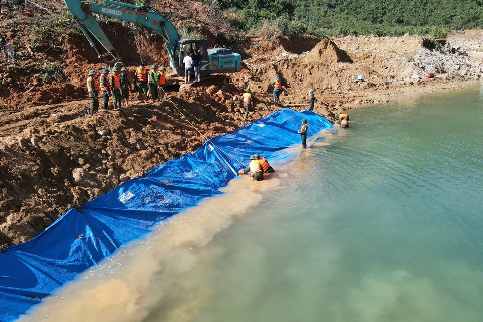 Lực lượng chức năng nắm dòng chảy mới được tạo nên để phục vụ công tác tìm kiếm dưới lòng suối Rào Trăng. (Ảnh: TTXVN phát)