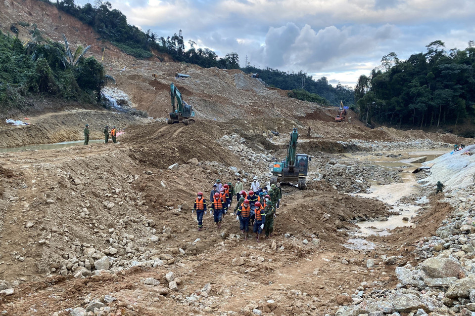 Lực lượng chức năng đưa thi thể nạn nhân ra khỏi hiện trường. (Ảnh: TTXVN phát)