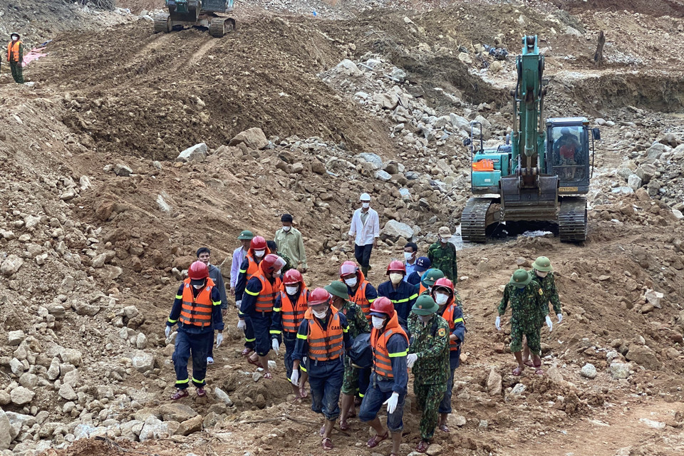 Lực lượng chức năng đưa thi thể nạn nhân ra khỏi hiện trường. (Ảnh: TTXVN phát)